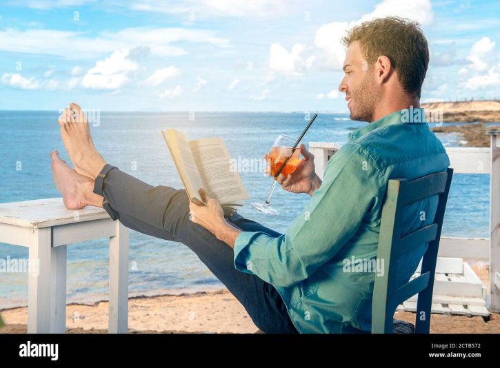 relaxed-man-reading-book-at-sea-enjoying-summer-vacations-on-beautiful-beach-guy-feeling-free-relaxed-and-happy-concept-of-vacations-freedom-happ-2CTB572